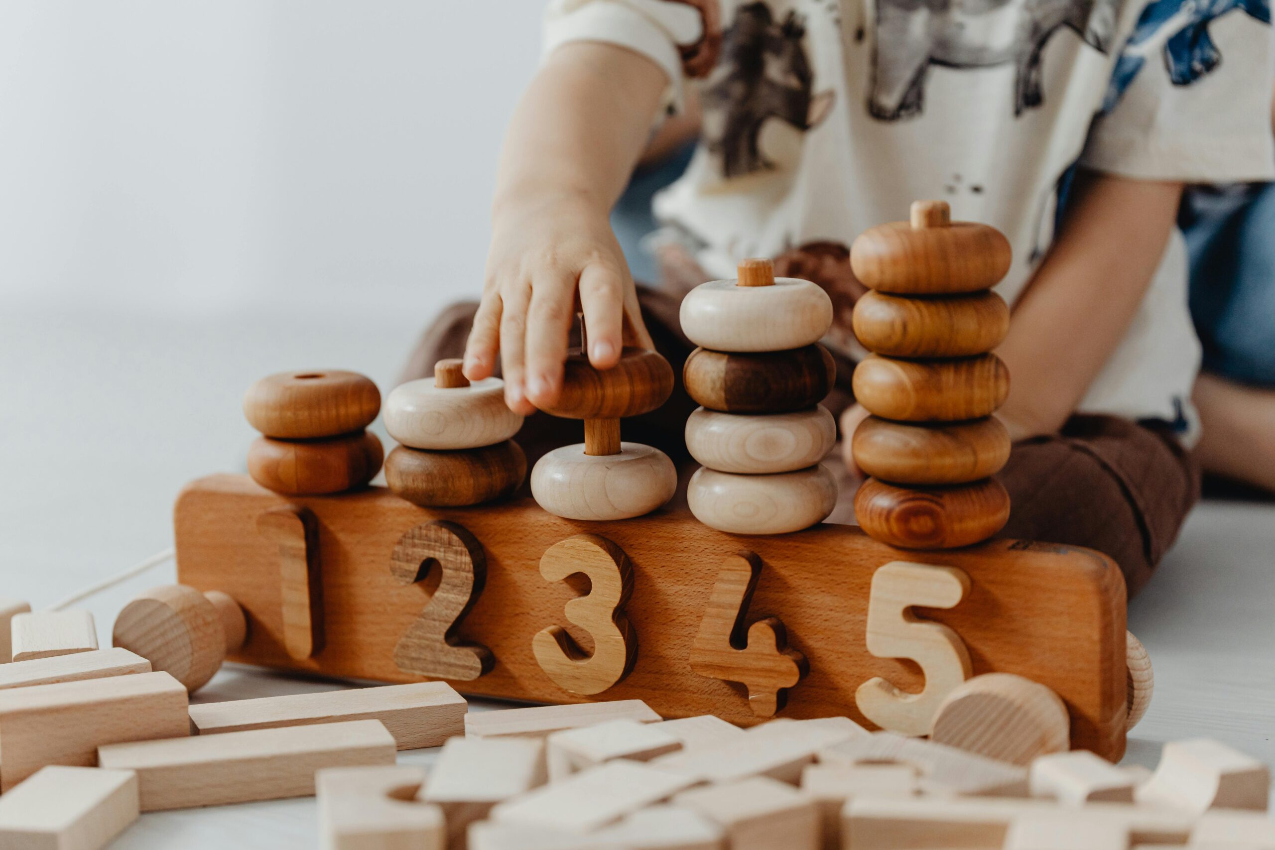 Child's hand interacting with wooden educational toys and number blocks indoors.